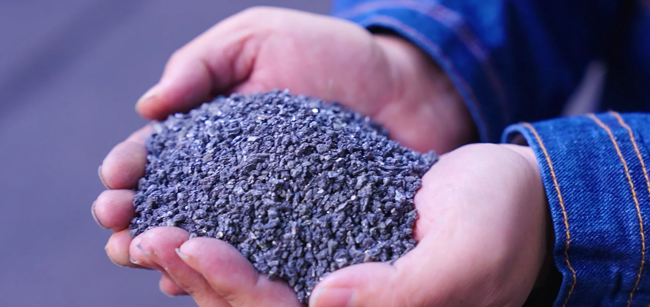 Hands presenting graphitized petroleum coke granules